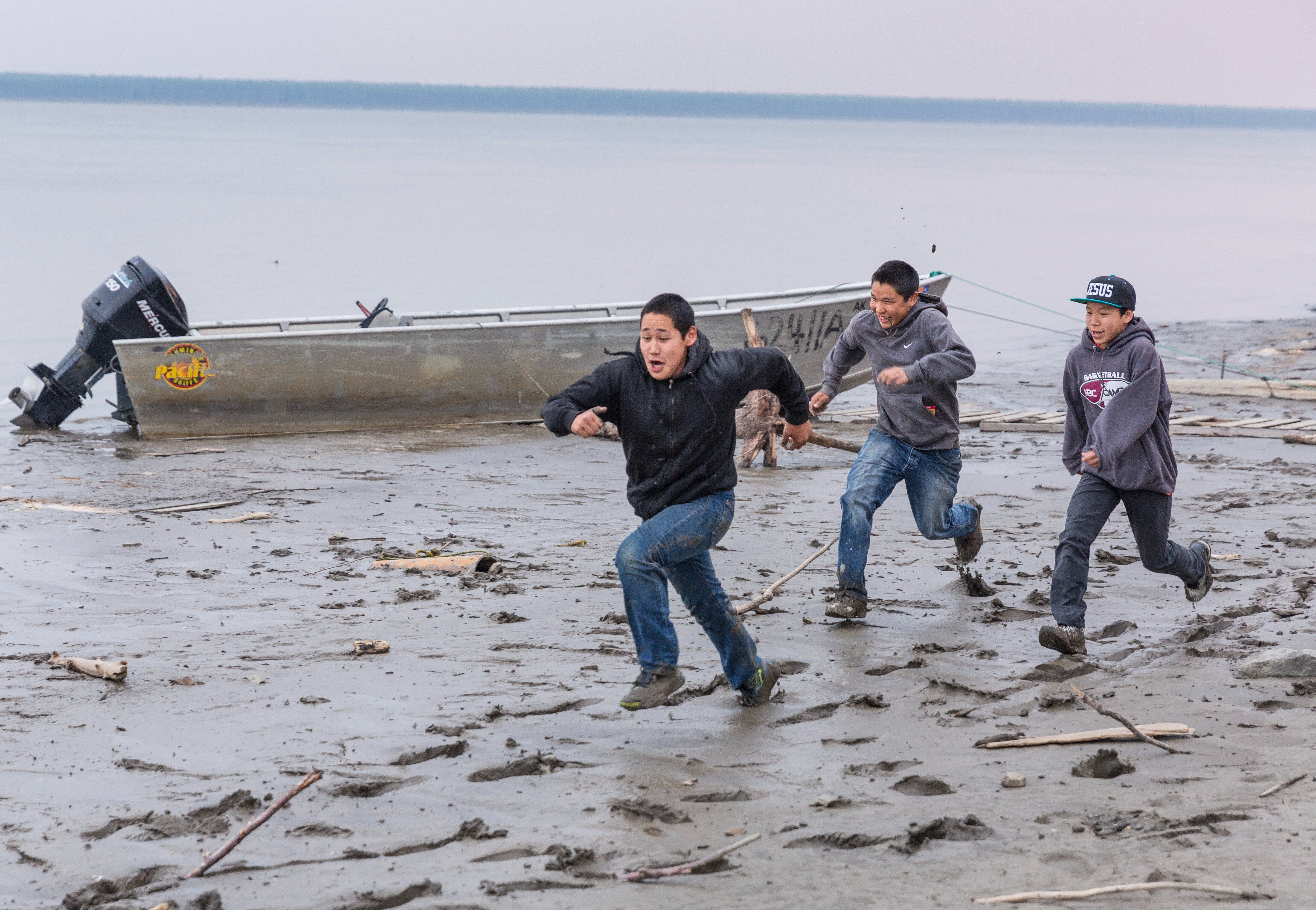 Three boys running down beach