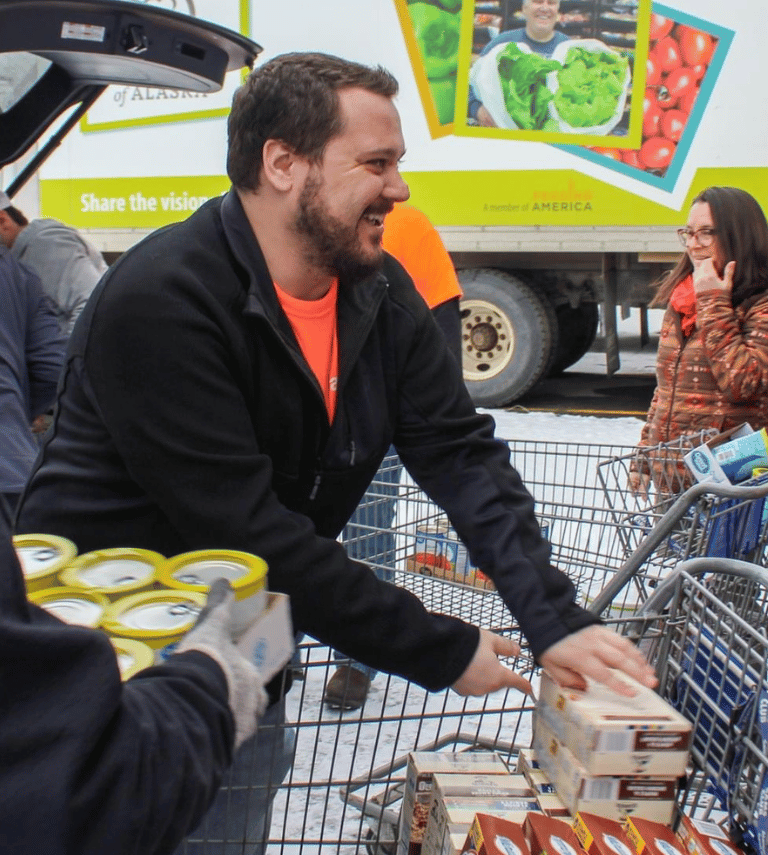 Man reaching over a cart to 