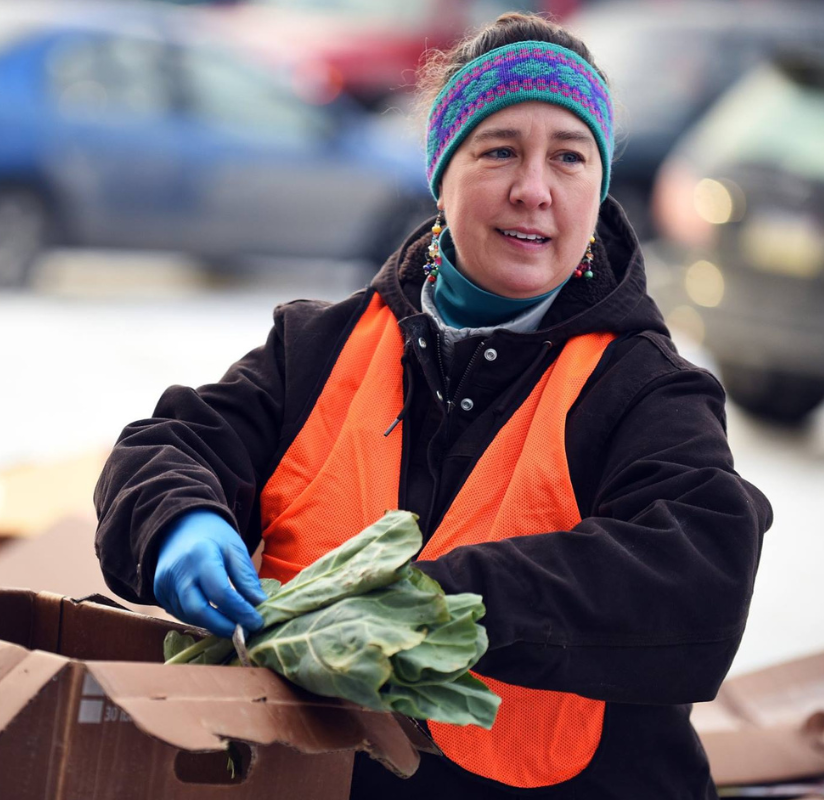 Woman in bandana and safety vest, sorting vegetables
